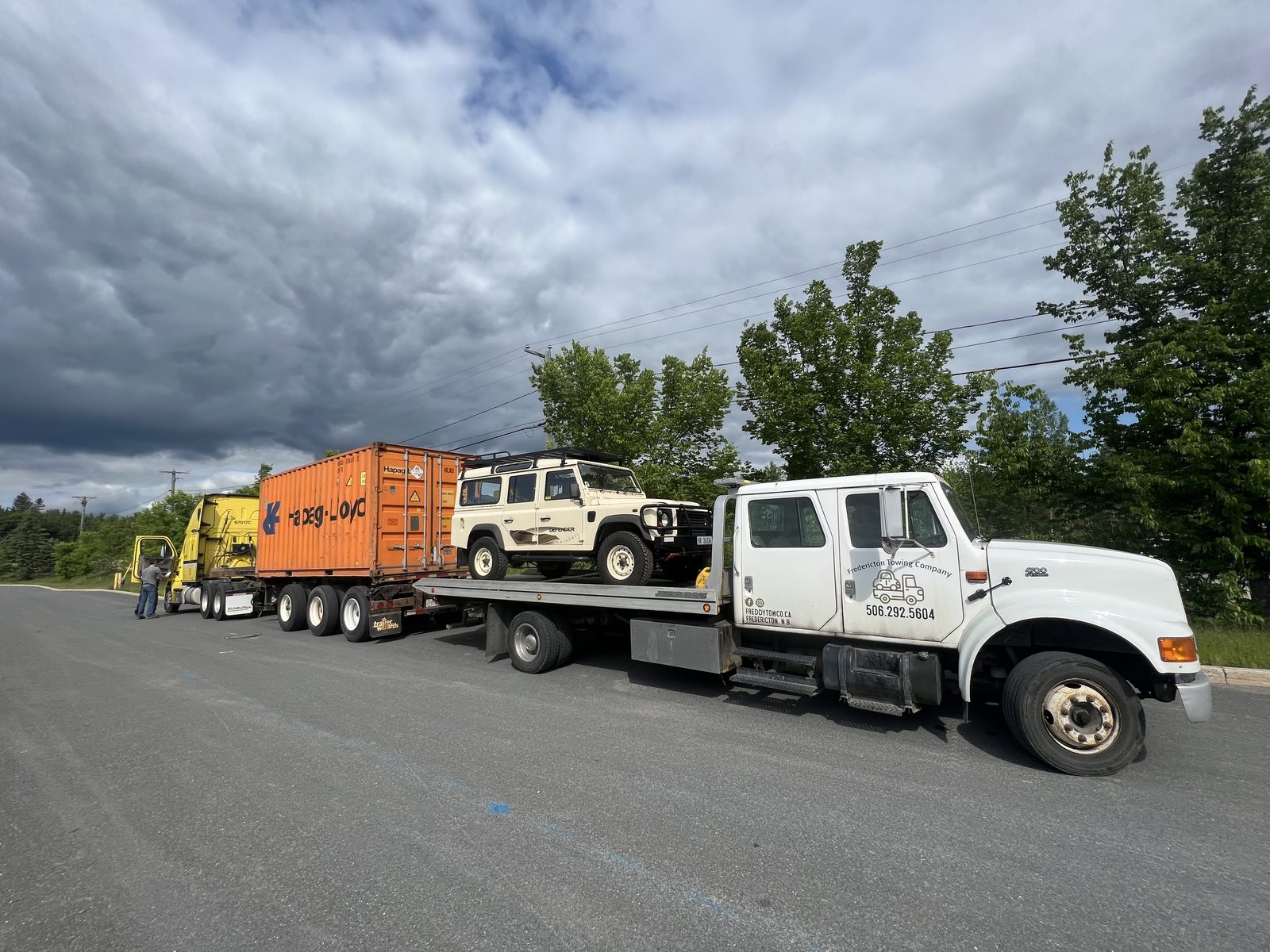 Freddy Tow Co. undecking heavy equipment from a trailer for a Fredericton-area customer.
